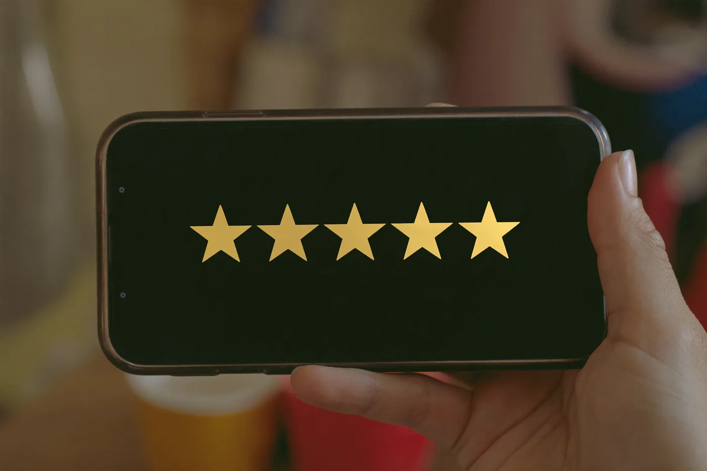 A smartphone showing a glowing five-star customer review — a review request that sends itself at the right moment
