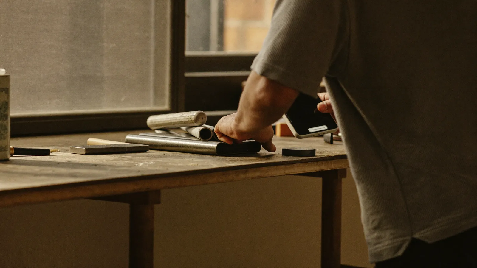 A Canterbury tradesperson pausing on a job to check a phone lighting up with a new customer enquiry